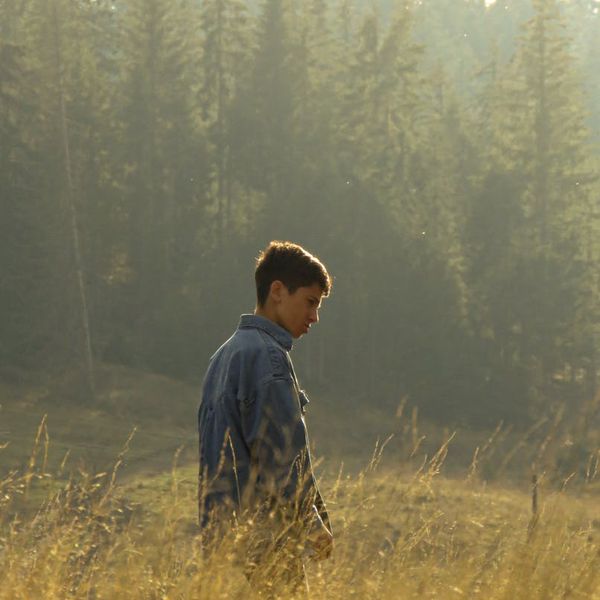 Man meditating outdoors with a serene natural background at sunrise.